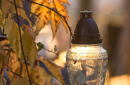 Eine Grablaterne mit gelblichen Blättern eines Baumes